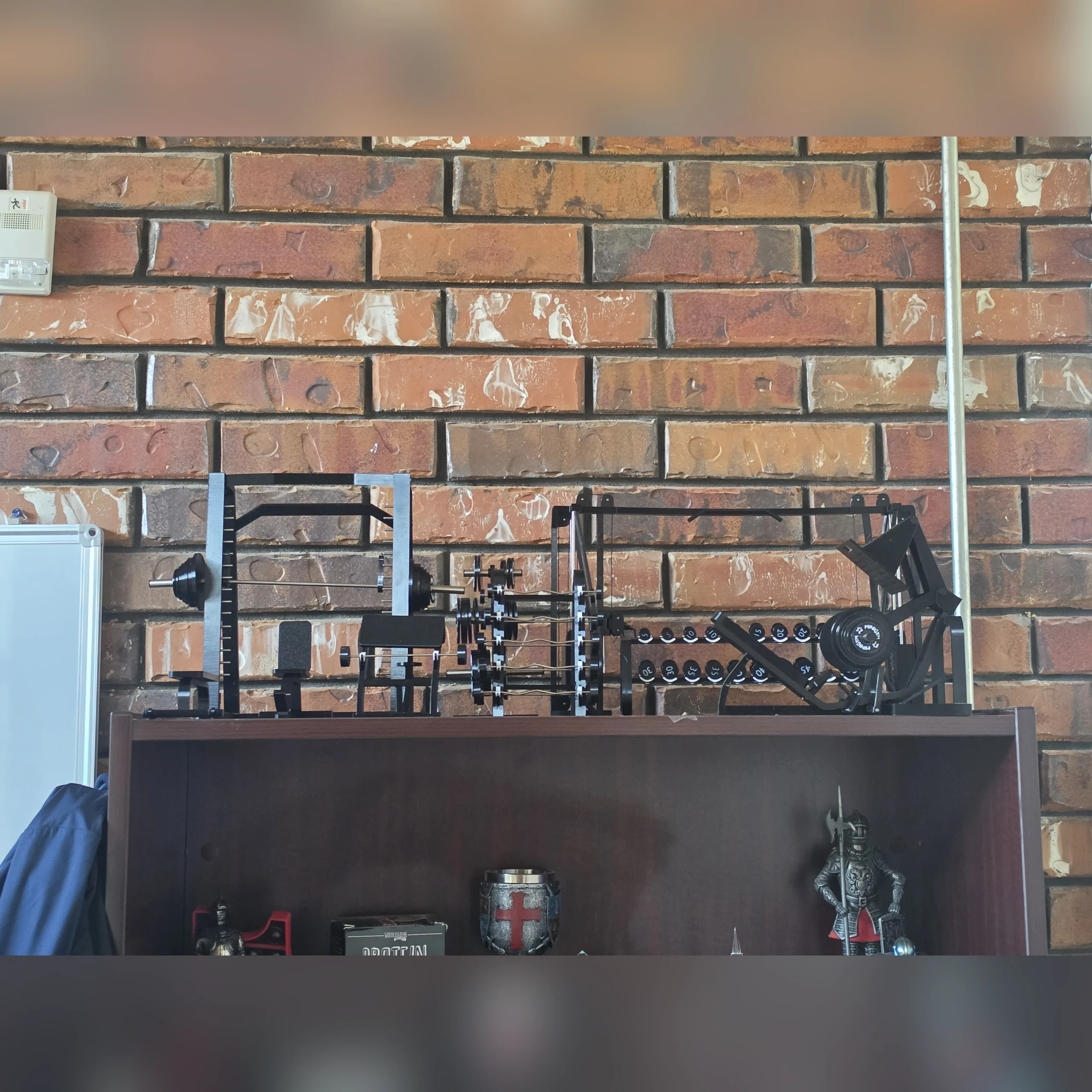Customer miniature gym collection arranged on a cabinet against a brick wall